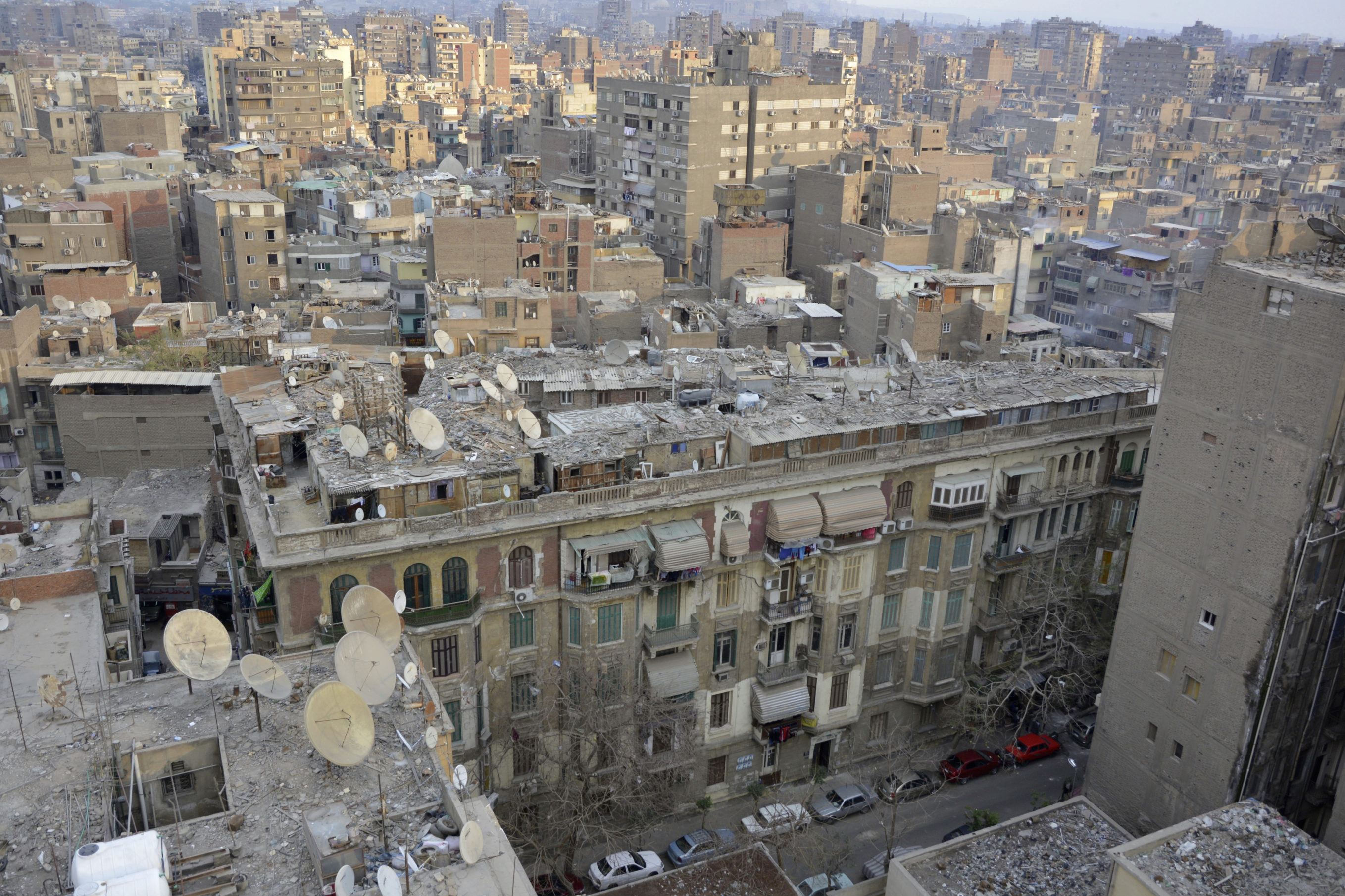 Cette photo a été prise au Caire, où un habitant sur deux est mal logé. Depuis les années 1950, l’afflux massif de population rurale venue habitée en ville fait exploser les bidonvilles qui finissent par également s’installer sur les toits. Son auteur, Pascal Garret, précise que l’immeuble n’est ici « ni un squat, ni un immeuble inoccupé. Les gravats sur le toit des baraques maintiennent les bâches et les tôles en cas de vent, lesquelles servent aussi de dépotoir ». 